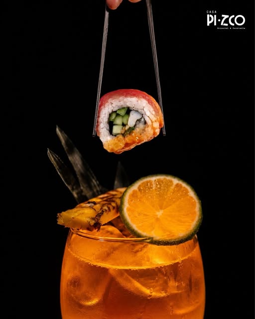 Un roll de sushi junto a un cóctel de Casa Pizco